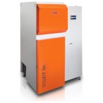 Kocioł na pellet HKS Lazar SmartFire 81 kW z ukosa: pomarańczowe drzwi, zasobnik 530 l w obudowie i wyświetlacz sterownika. Zdjęcie producenta
